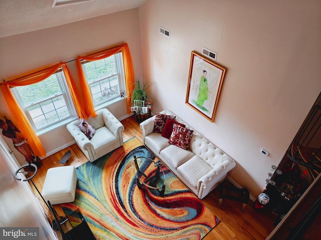 living room featuring visible vents, baseboards, and wood finished floors