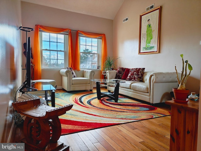 sitting room with lofted ceiling, wood-type flooring, and visible vents