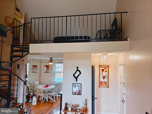 interior space featuring a high ceiling, a ceiling fan, and wood finished floors