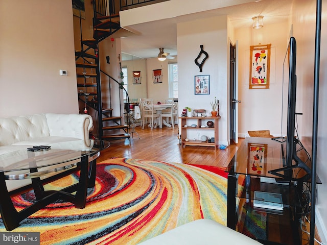 living area featuring ceiling fan, hardwood / wood-style floors, and stairs