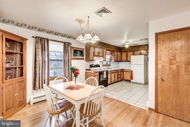 dining space with visible vents, ceiling fan with notable chandelier, light wood-style flooring, and a baseboard radiator