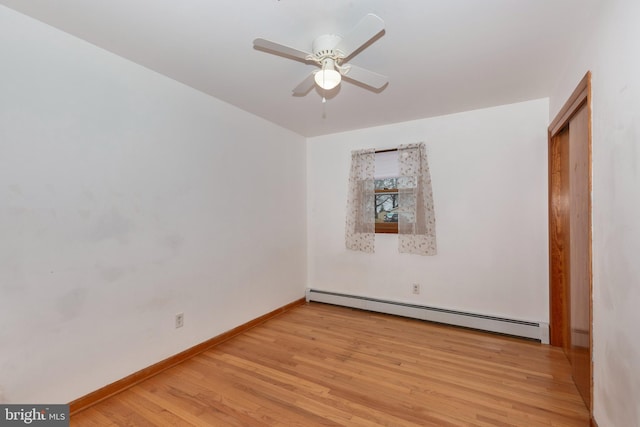 spare room with a baseboard heating unit, a ceiling fan, baseboards, and light wood finished floors