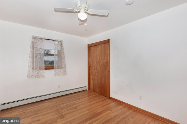 spare room featuring baseboards, a ceiling fan, light wood-type flooring, and a baseboard radiator