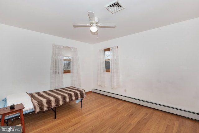 living area featuring ceiling fan, visible vents, baseboard heating, and wood finished floors