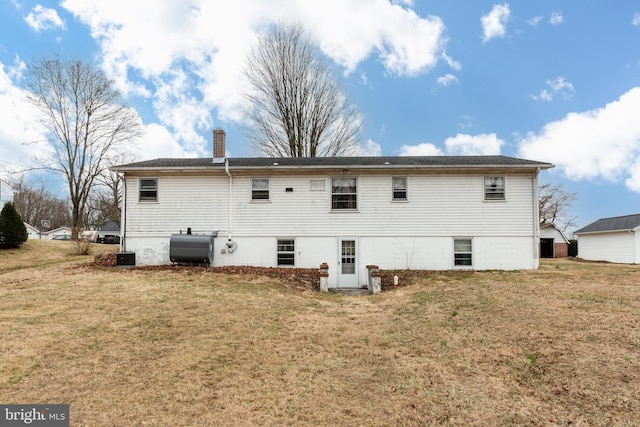 back of property with heating fuel, a yard, and a chimney