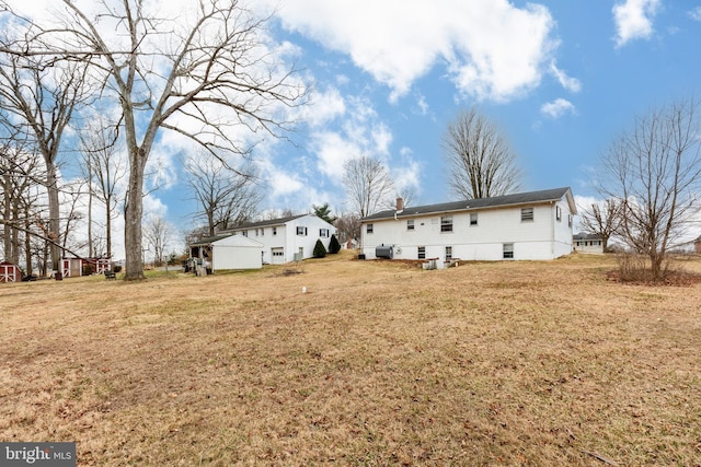 back of house featuring a lawn and a chimney