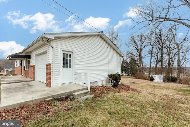 view of side of property featuring brick siding, driveway, a lawn, and an attached garage