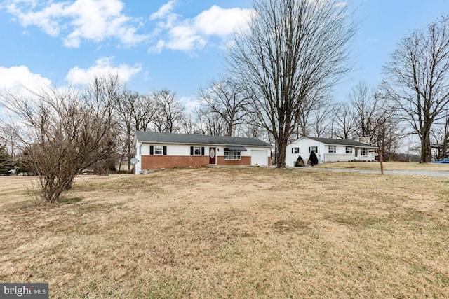 ranch-style home featuring a front lawn, an attached garage, and brick siding