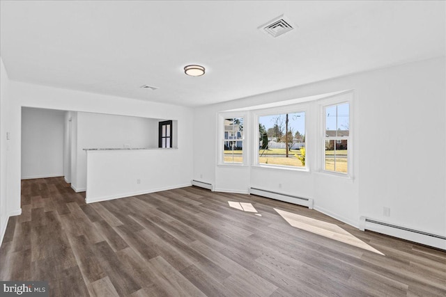 interior space with a baseboard radiator, visible vents, and wood finished floors