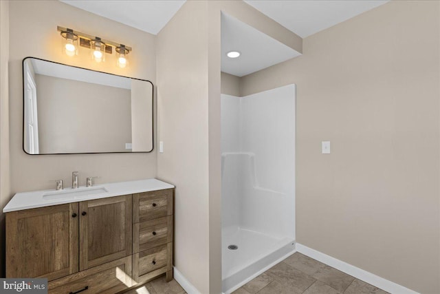 bathroom featuring vanity, baseboards, and a walk in shower