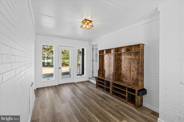 mudroom with crown molding, brick wall, and wood finished floors