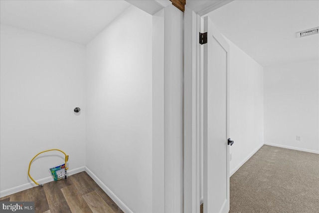 hallway featuring baseboards, visible vents, and wood finished floors