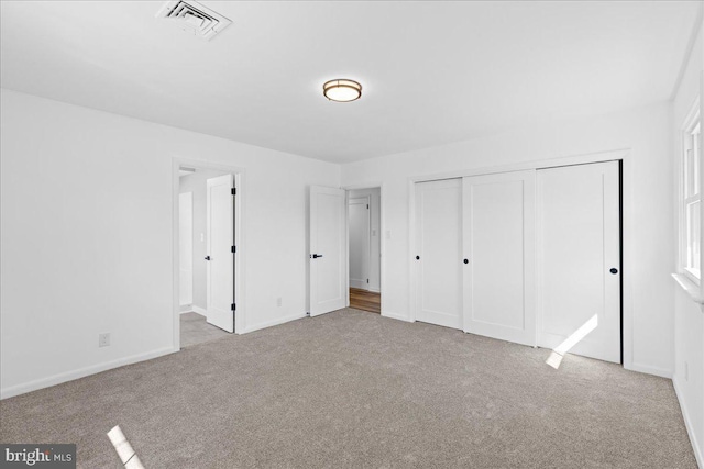 unfurnished bedroom featuring a closet, carpet flooring, visible vents, and baseboards