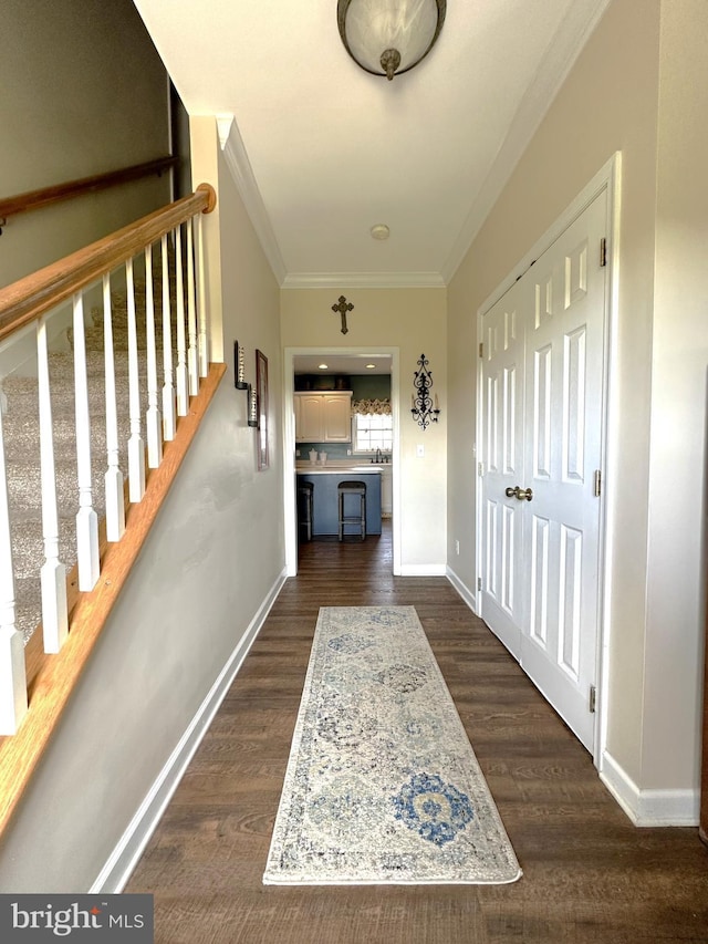 hall with ornamental molding, dark wood-type flooring, baseboards, and stairs