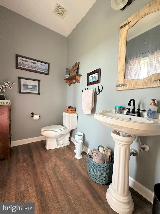 bathroom with toilet, baseboards, visible vents, and wood finished floors