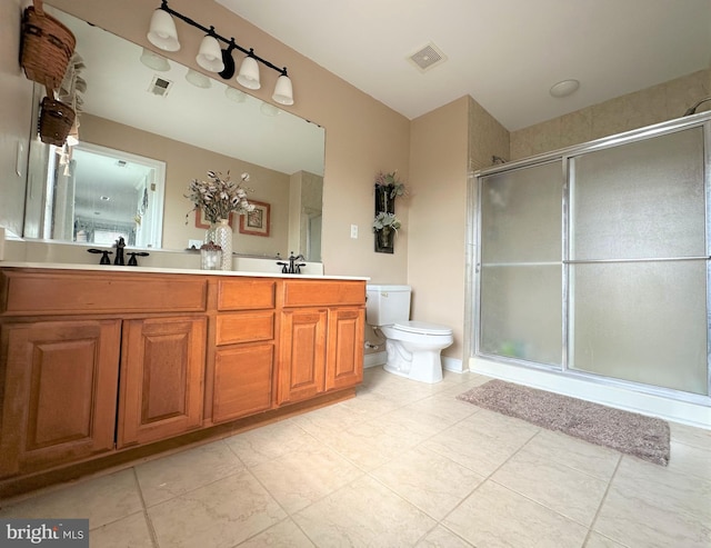 bathroom featuring toilet, a stall shower, a sink, and visible vents