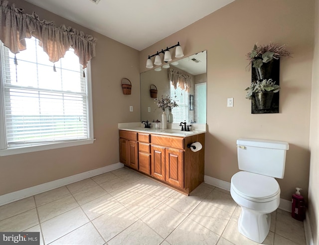 bathroom featuring double vanity, a sink, toilet, and baseboards