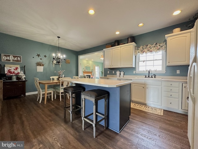 kitchen featuring a kitchen island, dark wood finished floors, white cabinets, and a sink