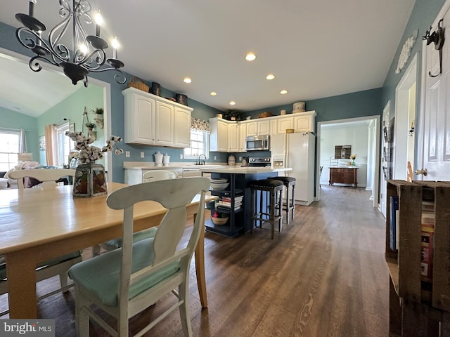 dining area featuring dark wood-style floors, vaulted ceiling, a notable chandelier, and recessed lighting