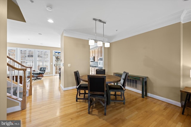 dining space featuring stairs, baseboards, crown molding, and light wood finished floors