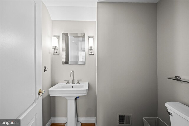 half bath featuring toilet, baseboards, and visible vents