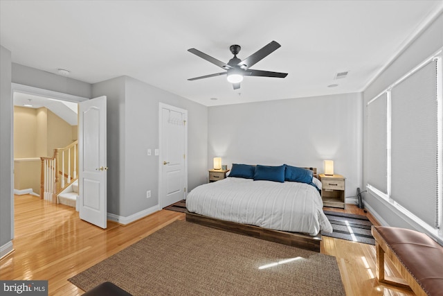 bedroom featuring a ceiling fan, light wood-style flooring, baseboards, and visible vents