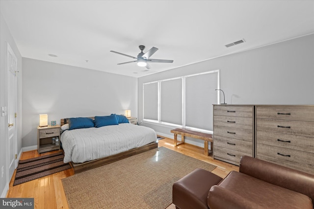 bedroom featuring light wood finished floors, visible vents, baseboards, and a ceiling fan