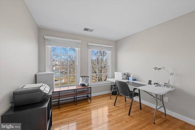 office area with light wood finished floors, visible vents, and baseboards