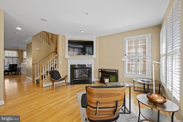 living area with wood finished floors, stairs, baseboards, and a premium fireplace