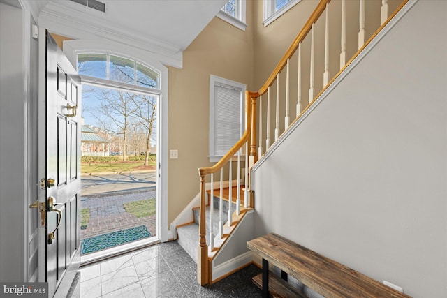 foyer entrance with baseboards, stairs, ornamental molding, a towering ceiling, and granite finish floor