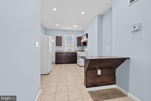 kitchen with light tile patterned flooring, recessed lighting, white appliances, baseboards, and wall chimney range hood