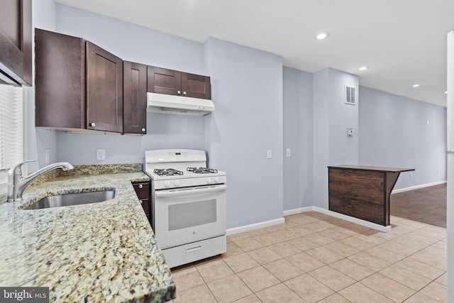 kitchen with visible vents, dark brown cabinets, white gas stove, under cabinet range hood, and a sink