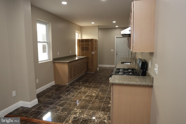 kitchen featuring gas stove, wall chimney range hood, recessed lighting, and baseboards