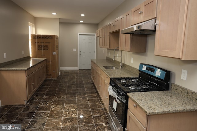 kitchen featuring light stone counters, recessed lighting, a sink, under cabinet range hood, and gas range