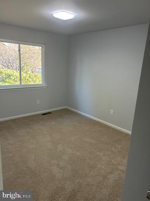 carpeted spare room featuring baseboards and visible vents