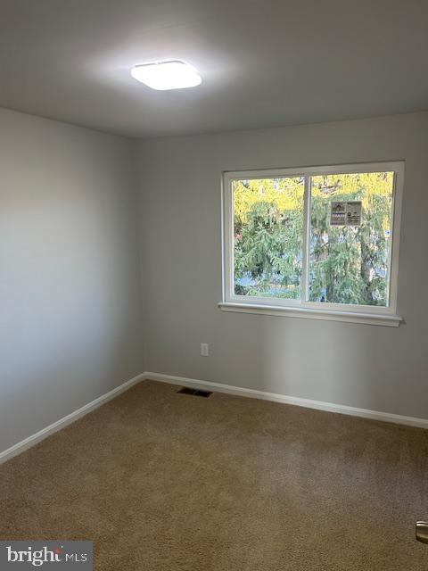 carpeted empty room featuring visible vents and baseboards