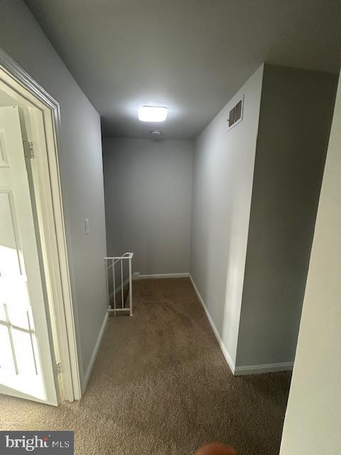 hallway with baseboards, visible vents, carpet flooring, and an upstairs landing