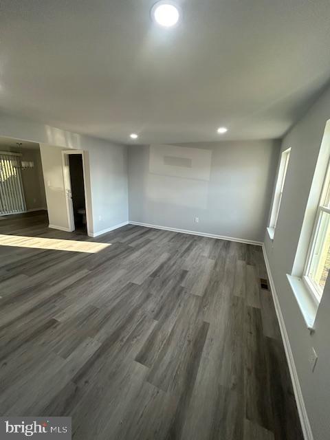 unfurnished room featuring dark wood-style floors, visible vents, and baseboards