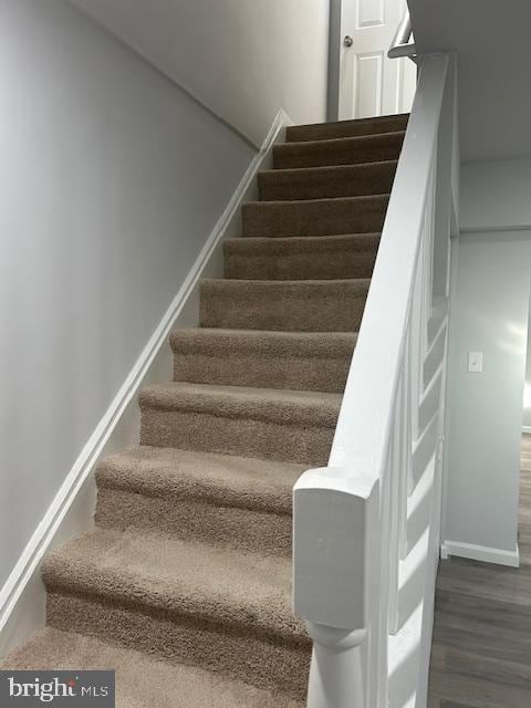 staircase featuring wood finished floors and baseboards