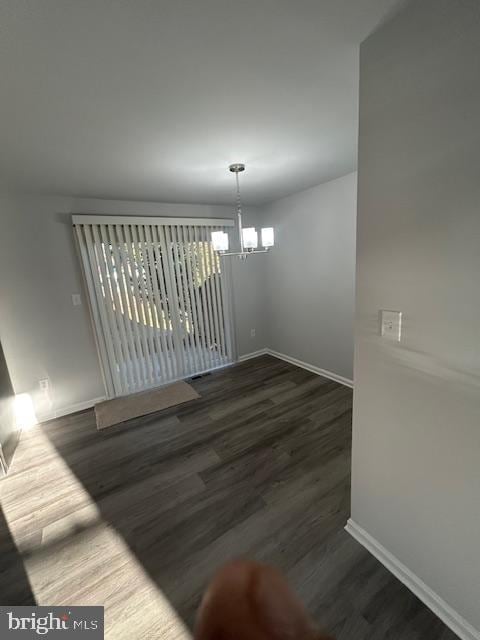 unfurnished dining area with baseboards, a chandelier, and wood finished floors