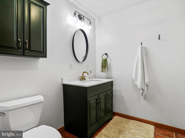 bathroom featuring baseboards, vanity, and toilet