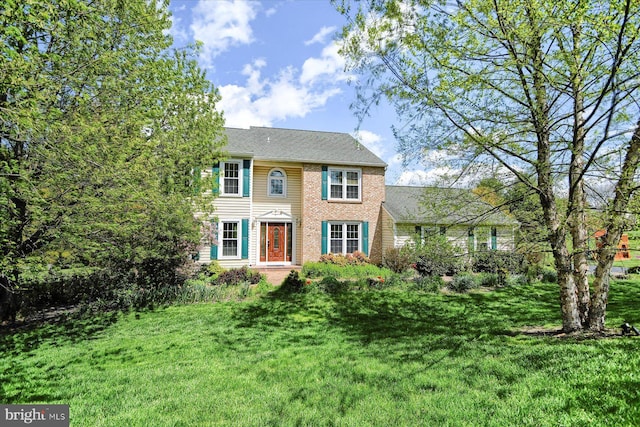 colonial home featuring brick siding and a front yard