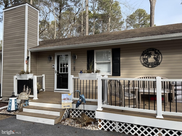 exterior space with a chimney and roof with shingles