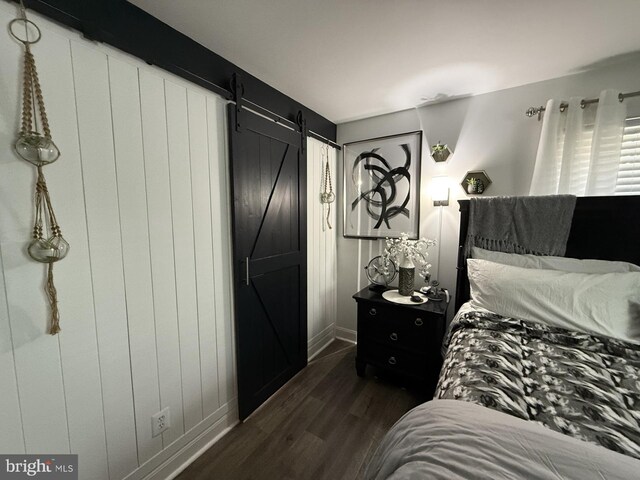 bedroom featuring a barn door and dark wood-type flooring