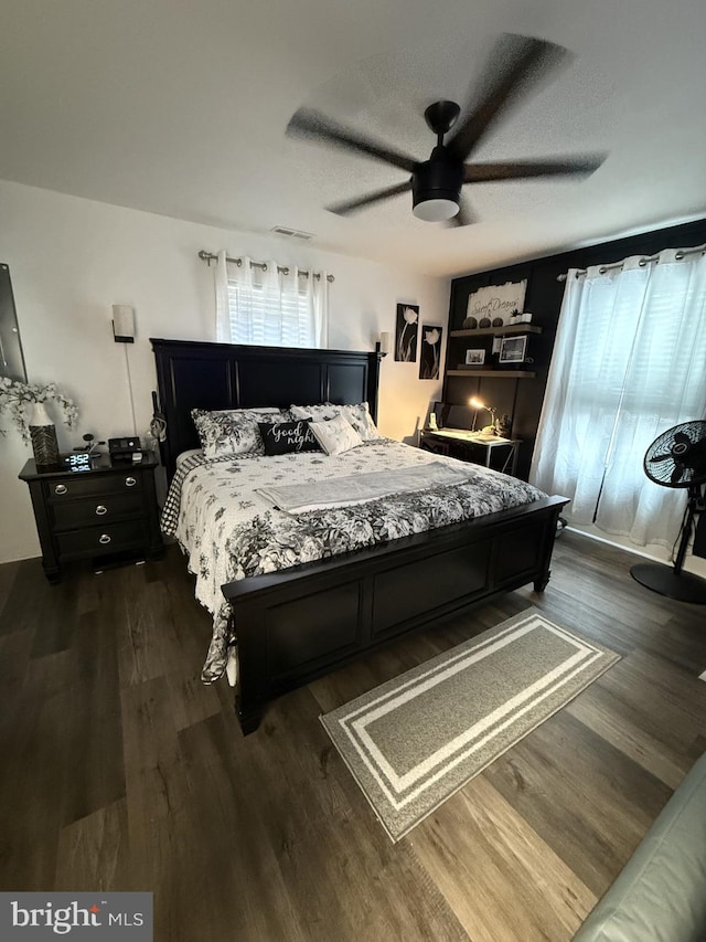 bedroom with ceiling fan, dark wood finished floors, and visible vents