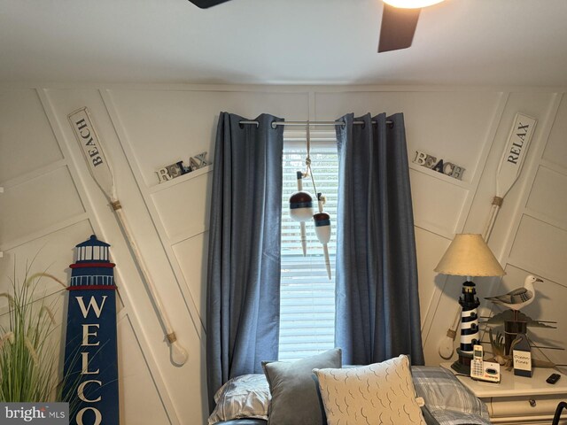 sitting room featuring a ceiling fan and a decorative wall