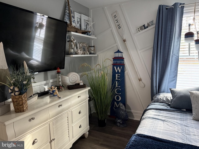 bedroom featuring dark wood finished floors and a decorative wall