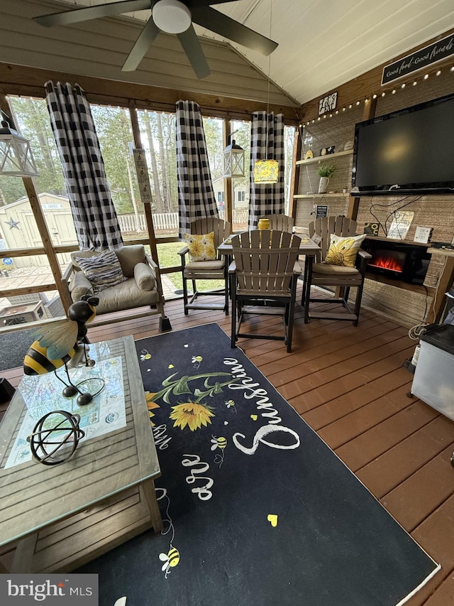 sunroom featuring lofted ceiling, a ceiling fan, and a glass covered fireplace