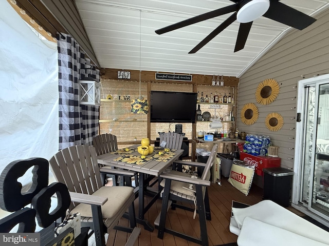 interior space featuring vaulted ceiling, ceiling fan, wood walls, and wood finished floors