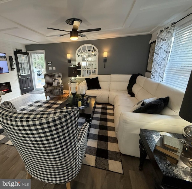 living area featuring a large fireplace, ceiling fan, and wood finished floors